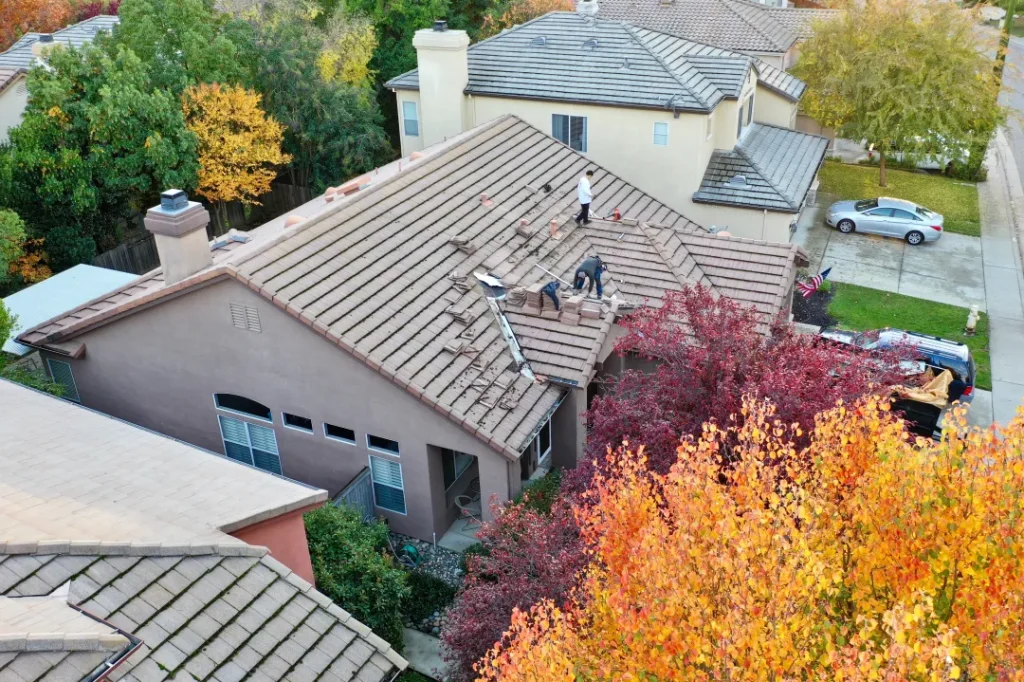 Roofers working on a concrete tile roof of a two-story home