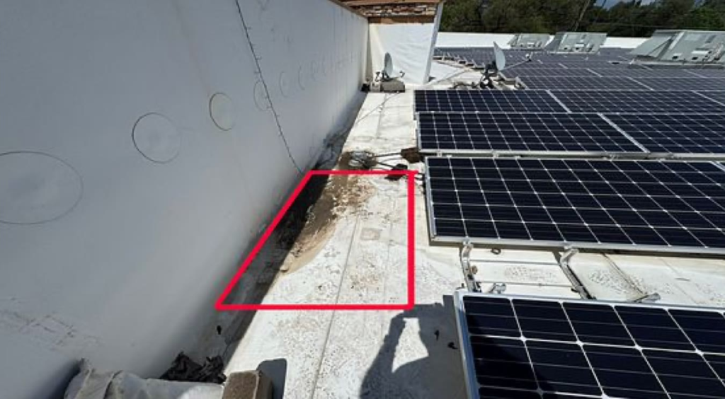 Soft spot outlined in red along the parapet wall of a commercial TPO flat roof with solar panels in Auburn