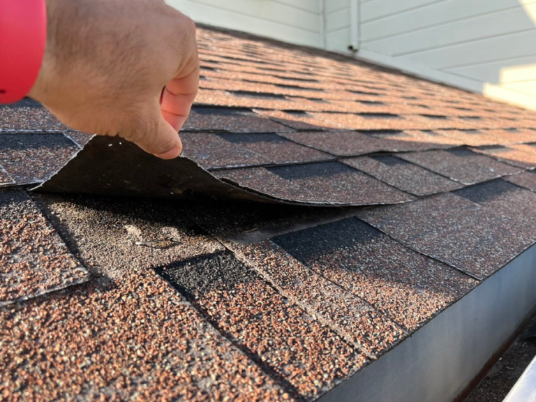 Shingle lifting by hand on an Elk Grove roof because the adhesive strips had failed