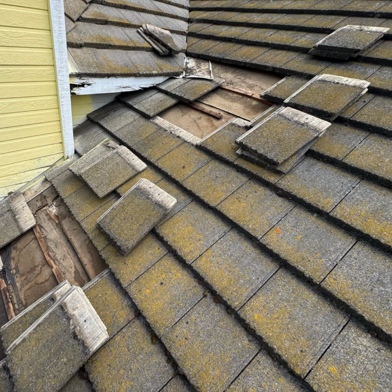 Tile roof by a chimney in Elk Grove with tiles removed, showing damaged underlayment and battens from clogged drainage channels