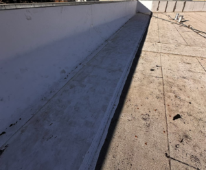 New white TPO membrane run up the parapet wall of a commercial flat roof in Marysville after a leak repair