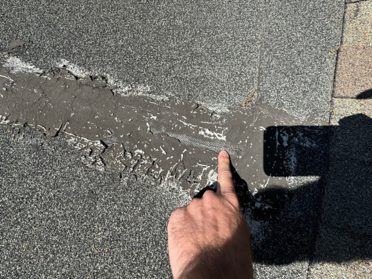 Old patch in the low-slope cricket of a Rocklin shingle roof wearing out and causing a leak