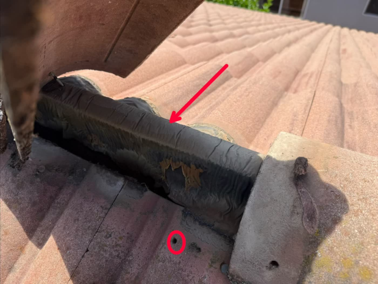 Worn, peeling flash band under a tile ridge on a Rocklin roof, with an exposed nail hole circled in the top row of tile