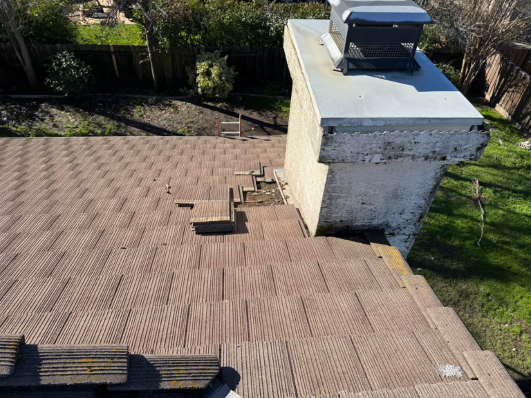 Clogged drainage channel beside a chimney on a Rocklin tile roof that caused dry rot