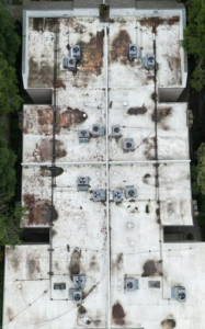 Drone view of a worn, stained commercial TPO flat roof in Sacramento before replacement