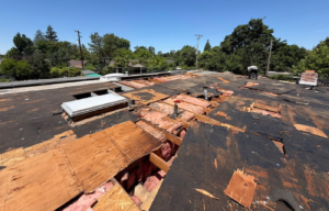 Sacramento flat roof torn off, showing damaged decking being replaced