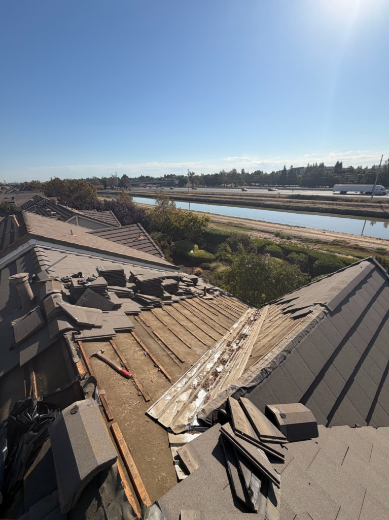 Tiles removed along a Sacramento tile roof valley, showing dry-rotted battens and worn underlayment